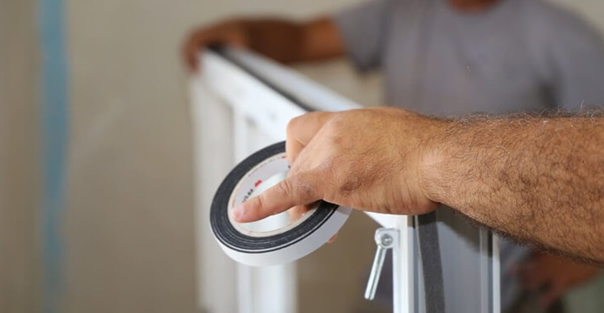 L’artisan fixe du compriband tout autour de la fenêtre