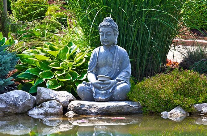 Une statue de Bouddha en bronze dans un jardin japonais