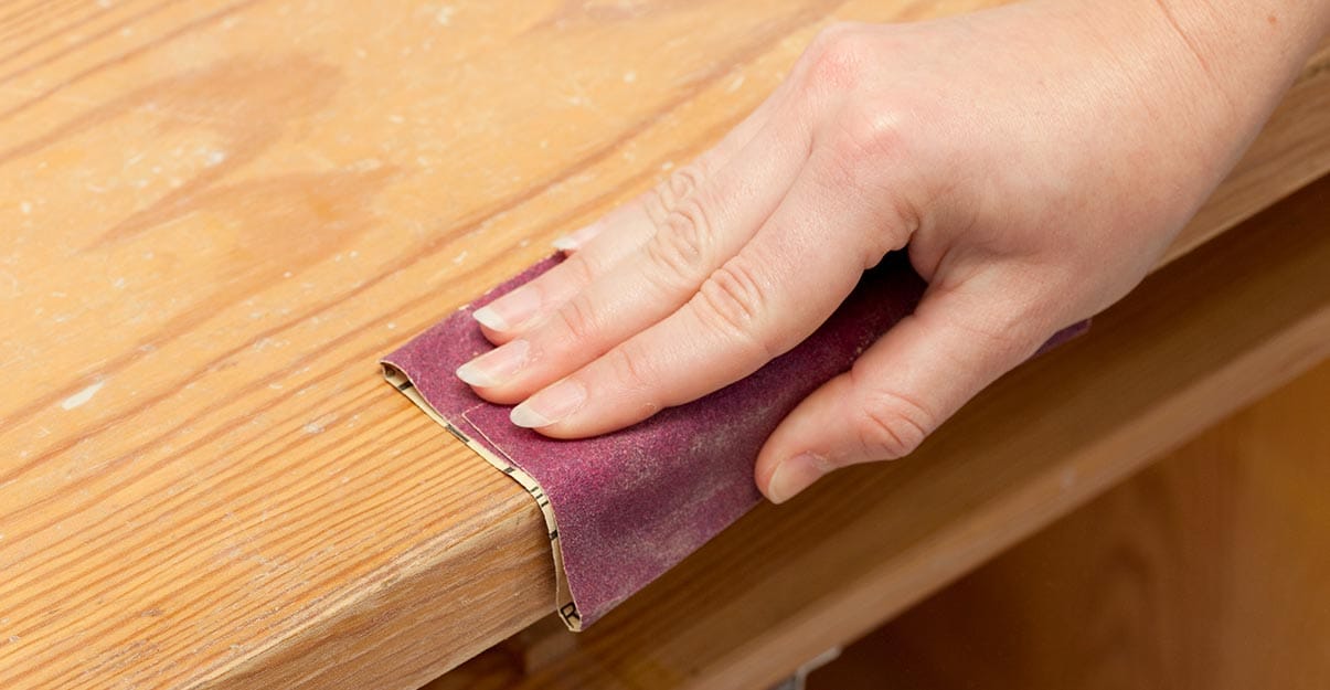 Poncer du bois à la main avec un morceau de papier de verre