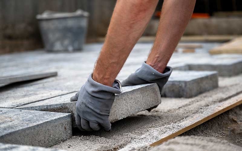 Maçon en traine de poser des pavés en pierre