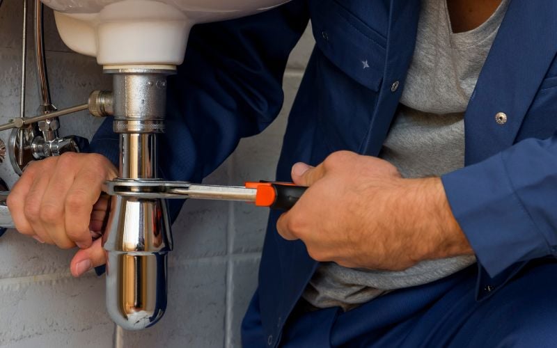 Plombier installant un siphon d'évier